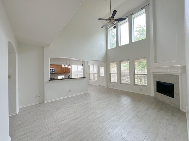 5310 Flagridge Ln, Houston, TX 77066 - unfurnished living room featuring a towering ceiling, ceiling fan, light wood-style floors, a tiled fireplace, and baseboards