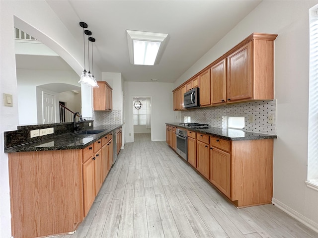 5310 Flagridge Ln, Houston, TX 77066 - kitchen with stainless steel appliances, a sink, light wood finished floors, tasteful backsplash, and dark stone counters