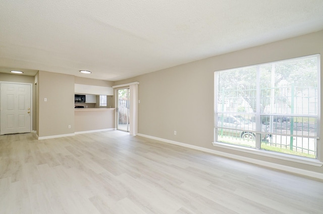 1950 Spenwick Dr Unit 302, Houston, TX 77055 - unfurnished living room featuring baseboards, light wood finished floors, and a textured ceiling