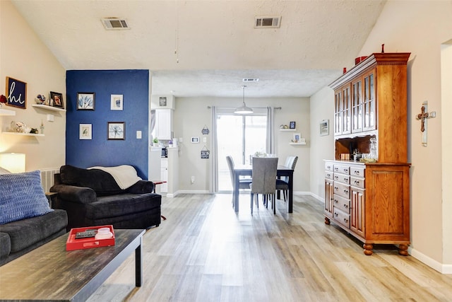 living area featuring baseboards, light wood-style flooring, and visible vents