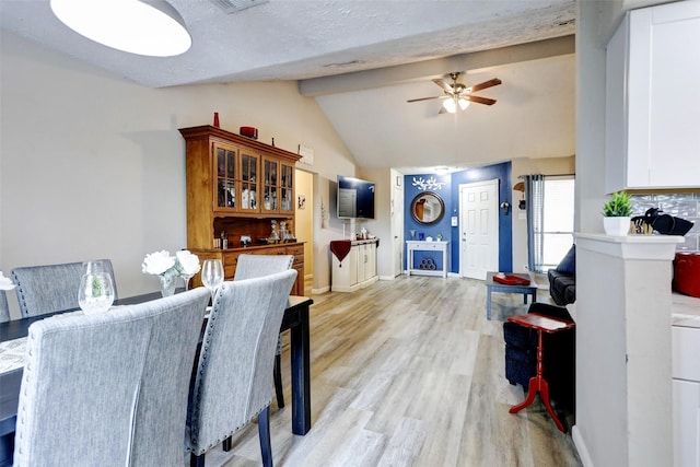 dining room with ceiling fan, lofted ceiling with beams, baseboards, and light wood-type flooring