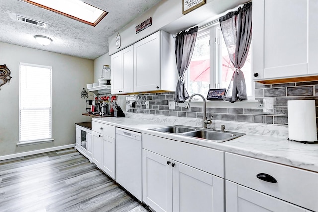 kitchen featuring visible vents, white cabinetry, tasteful backsplash, a sink, and dishwasher