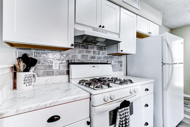 kitchen featuring white range with gas cooktop, under cabinet range hood, white cabinets, and tasteful backsplash