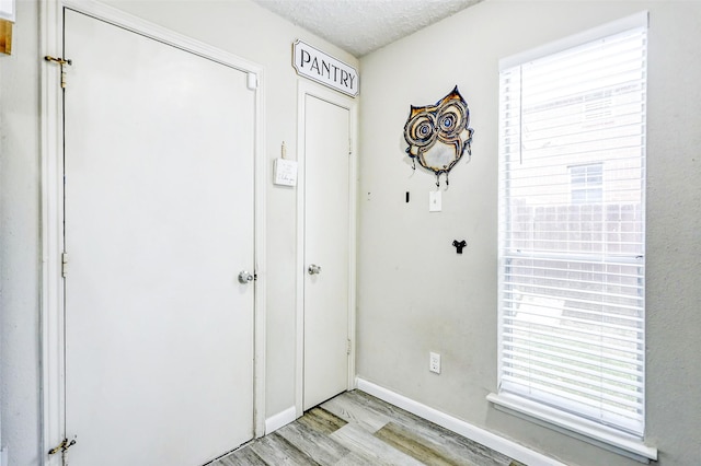 entrance foyer featuring a textured ceiling, baseboards, and light wood-type flooring