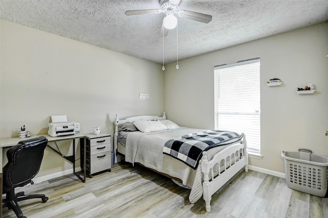 bedroom with ceiling fan, a textured ceiling, baseboards, and light wood-style flooring