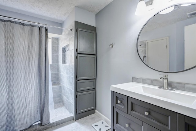 full bath with vanity, tile patterned floors, a tile shower, and a textured ceiling