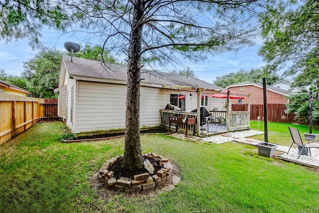 rear view of house featuring a fenced backyard, a yard, and a fire pit