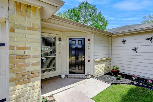 property entrance with brick siding and roof with shingles