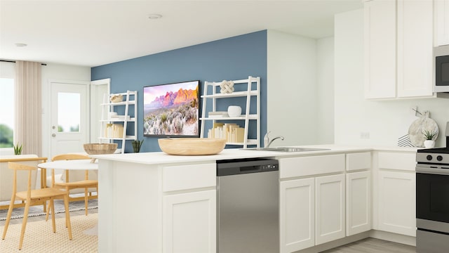 kitchen with a sink, white cabinets, stainless steel appliances, and a peninsula