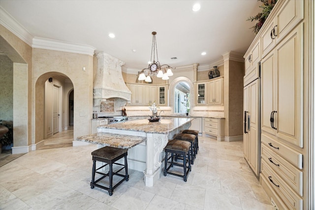 25 Kings Lake Estates Blvd, Humble, TX 77346 - kitchen with custom range hood, a kitchen island with sink, cream cabinetry, and a breakfast bar