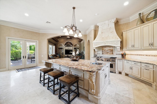 25 Kings Lake Estates Blvd, Humble, TX 77346 - kitchen with arched walkways, ornamental molding, premium range hood, cream cabinetry, and a center island with sink