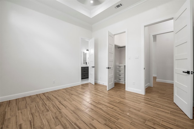 58-D Hickory Ridge Dr, Huffman, TX 77336 - unfurnished bedroom featuring crown molding, visible vents, a walk in closet, and light wood-style floors