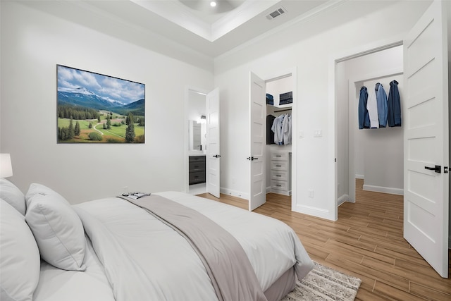 58-D Hickory Ridge Dr, Huffman, TX 77336 - bedroom with a walk in closet, light wood-type flooring, a tray ceiling, visible vents, and ornamental molding