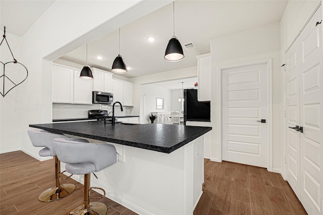 kitchen featuring dark wood-style flooring, dark countertops, appliances with stainless steel finishes, white cabinetry, and visible vents
