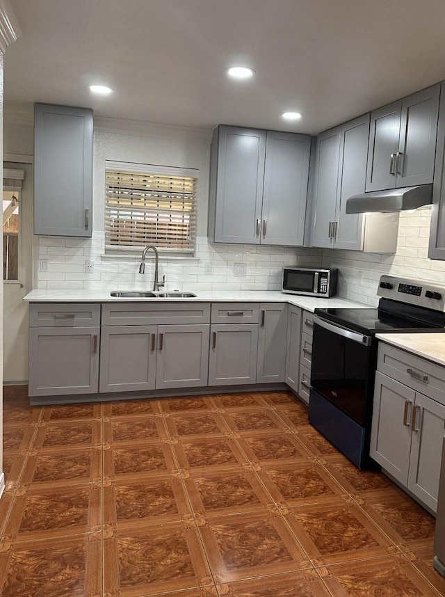 kitchen featuring a sink, gray cabinets, stainless steel appliances, decorative backsplash, and under cabinet range hood