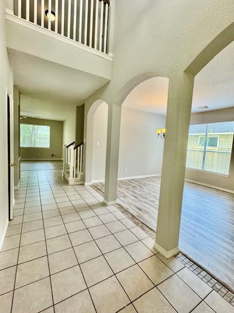 unfurnished room with baseboards, arched walkways, a high ceiling, and tile patterned floors