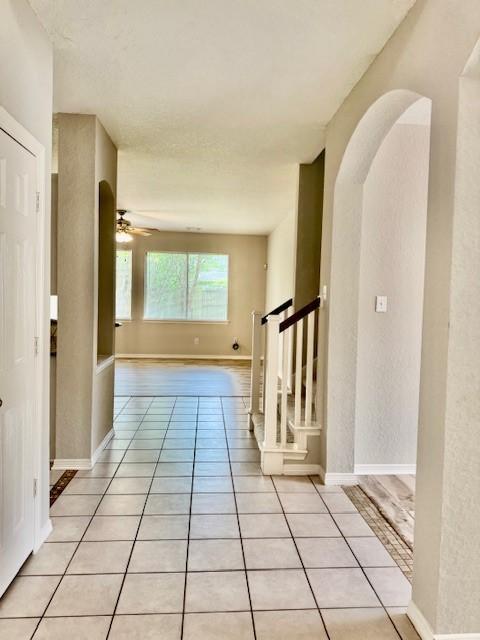 hallway with baseboards, stairs, and light tile patterned flooring