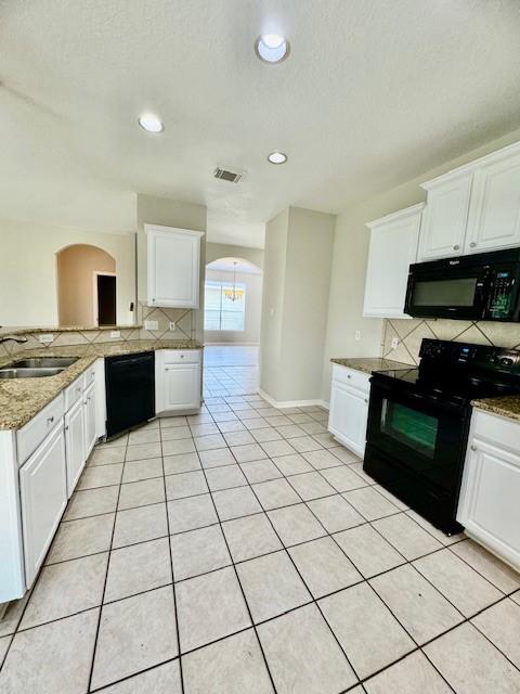 kitchen with backsplash, visible vents, arched walkways, a sink, and black appliances