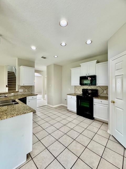 kitchen featuring decorative backsplash, recessed lighting, white cabinets, a sink, and black appliances