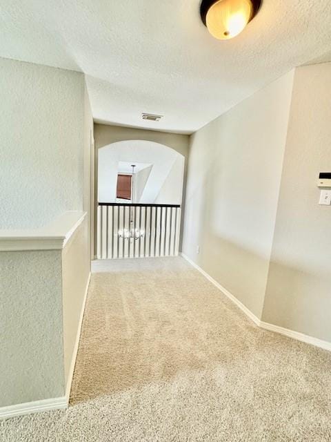 carpeted spare room with visible vents, a textured ceiling, a textured wall, and baseboards