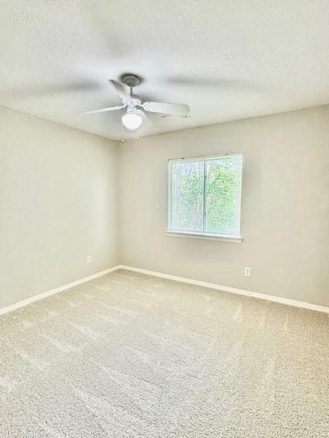 unfurnished room with baseboards, ceiling fan, and a textured ceiling