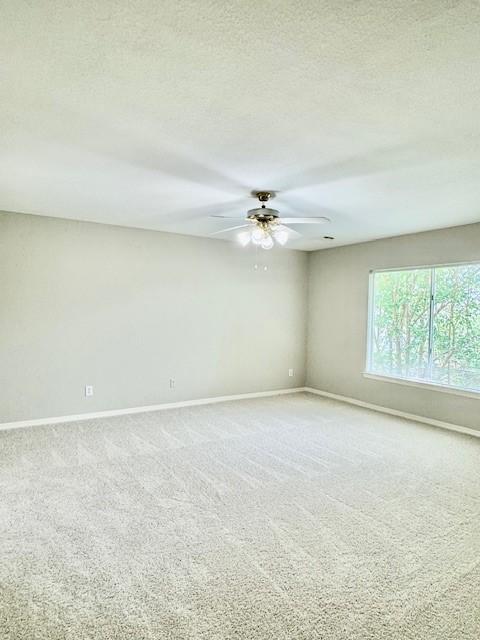 carpeted spare room with a ceiling fan, baseboards, and a textured ceiling