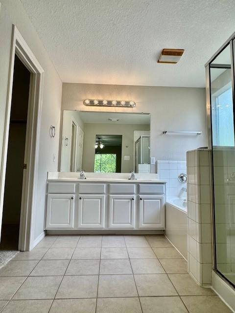 bathroom featuring a garden tub, a textured ceiling, tile patterned flooring, and a stall shower