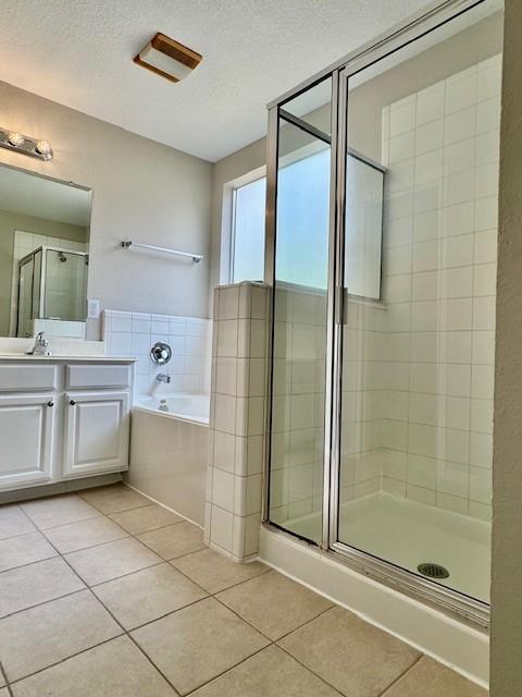 bathroom featuring a garden tub, a textured ceiling, tile patterned flooring, a shower stall, and vanity