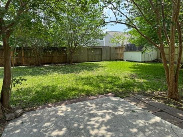 view of yard featuring a patio, an outbuilding, a shed, and a fenced backyard