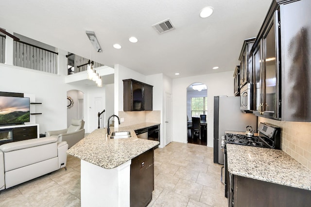 kitchen with dark brown cabinets, a sink, arched walkways, a peninsula, and open floor plan