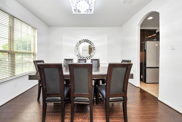 dining area with baseboards, arched walkways, and dark wood finished floors