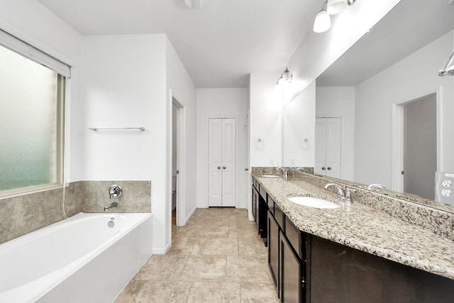 full bathroom with double vanity, a sink, a bath, and a closet