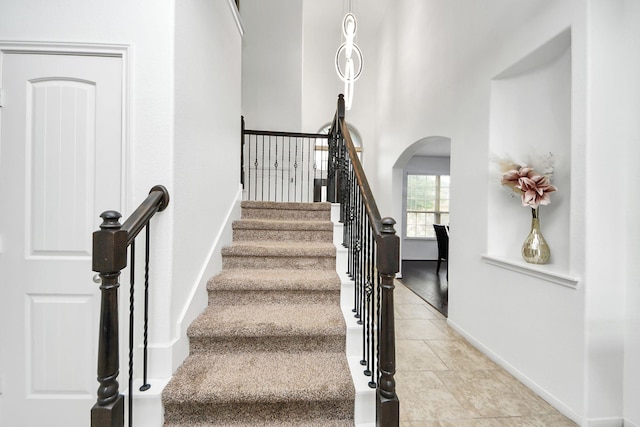 staircase featuring arched walkways and baseboards
