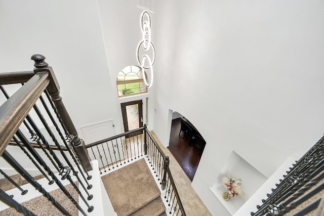stairway with tile patterned flooring and a towering ceiling