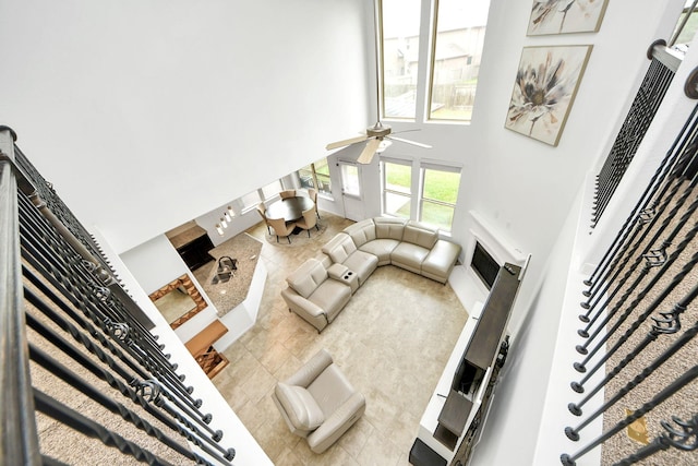 tiled living area featuring ceiling fan and a towering ceiling