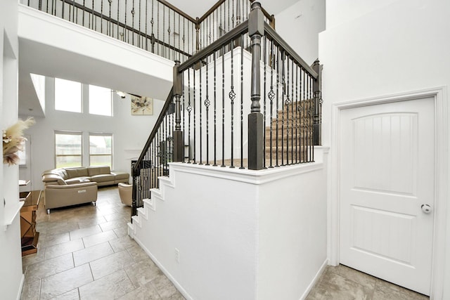 stairway featuring baseboards and a high ceiling