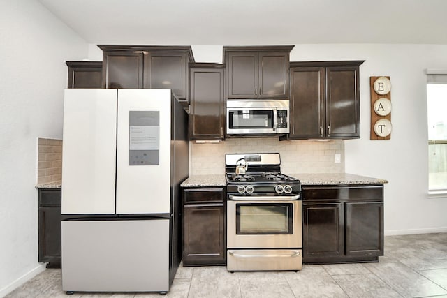 kitchen featuring dark brown cabinetry, light stone countertops, baseboards, tasteful backsplash, and stainless steel appliances