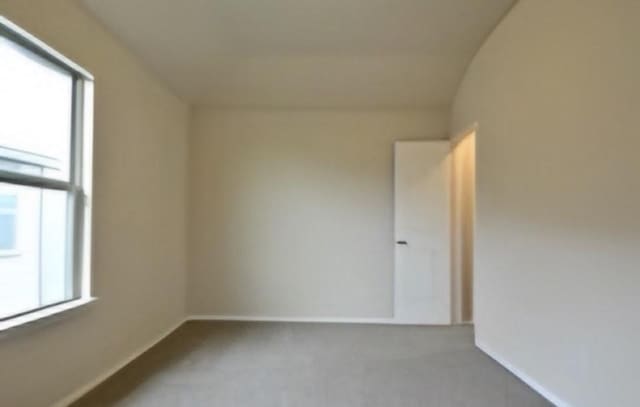 carpeted spare room featuring baseboards