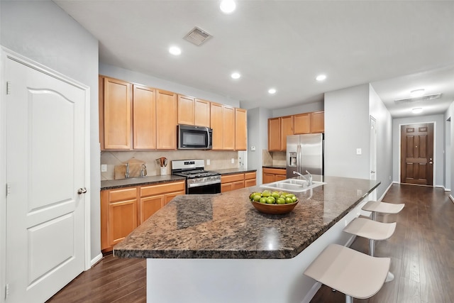 22507 Bellwick Ridge Ln, Katy, TX 77449 - kitchen featuring a kitchen bar, dark wood-style flooring, visible vents, appliances with stainless steel finishes, and a sink