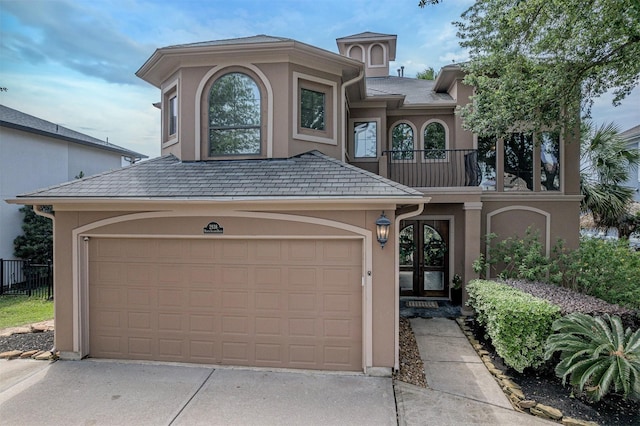 mediterranean / spanish-style home with concrete driveway, a garage, a balcony, and stucco siding