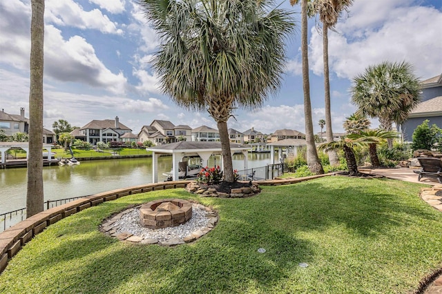 view of yard featuring a boat dock, a water view, a residential view, and an outdoor fire pit