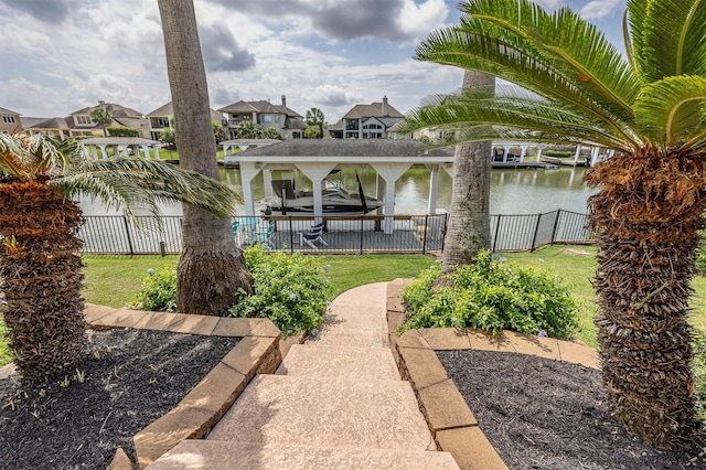 exterior space featuring a water view, fence, boat lift, and a residential view