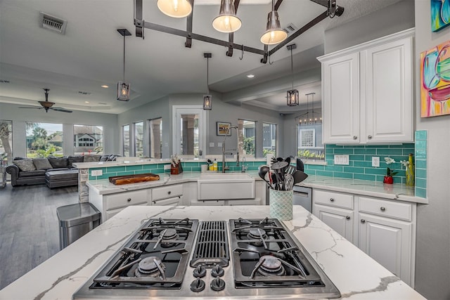 kitchen with white cabinets, stovetop with downdraft, a ceiling fan, open floor plan, and visible vents