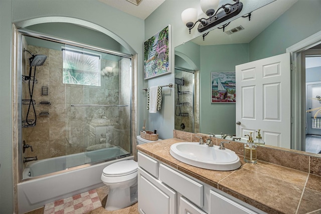 full bathroom with vanity, combined bath / shower with glass door, toilet, and visible vents