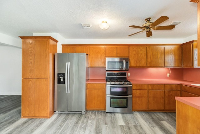 123 S Yaupon St, Lake Jackson, TX 77566 - kitchen featuring brown cabinetry, a ceiling fan, visible vents, appliances with stainless steel finishes, and light wood-type flooring
