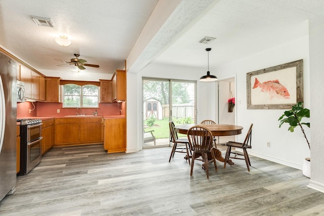 123 S Yaupon St, Lake Jackson, TX 77566 - dining space featuring light wood finished floors, a textured ceiling, a ceiling fan, baseboards, and visible vents