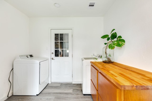 123 S Yaupon St, Lake Jackson, TX 77566 - clothes washing area with light wood-style floors, separate washer and dryer, cabinet space, and visible vents