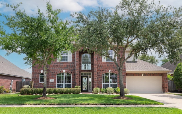 colonial-style house with a garage, a front lawn, fence, brick siding, and concrete driveway