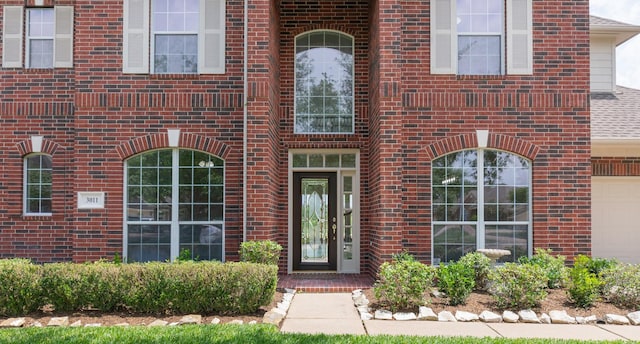 property entrance featuring a garage and brick siding