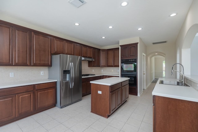kitchen featuring dobule oven black, visible vents, stainless steel refrigerator with ice dispenser, arched walkways, and a sink